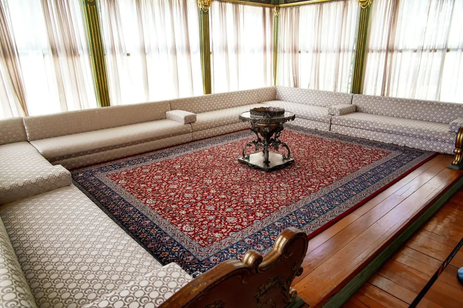 Inside the Sofa Pavilion: divans around a carpet and a brazier, curtains drawn across the windows.