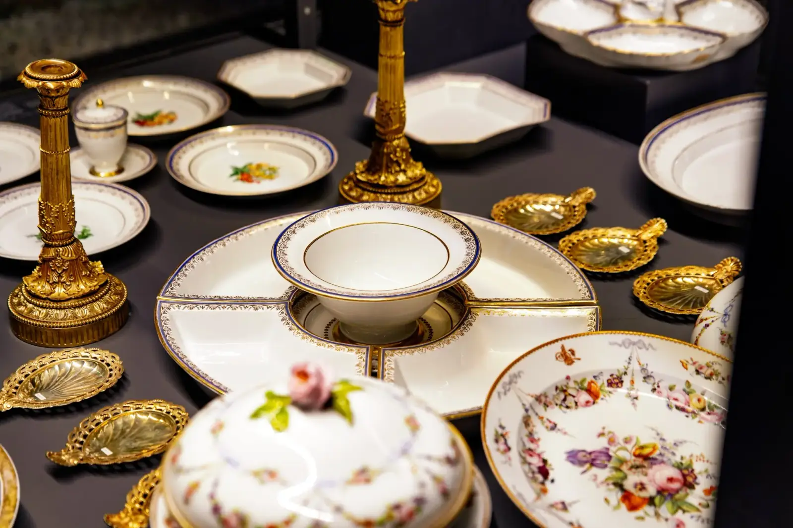 European porcelain plates and gilt candlesticks laid out in the collection.