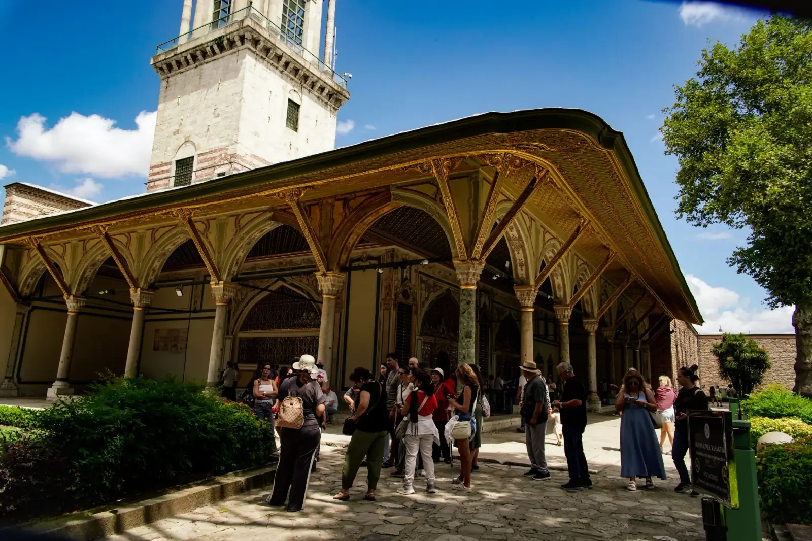 The painted portico of the Imperial Council, visitors beneath its gilded eaves and the Tower of Justice behind.