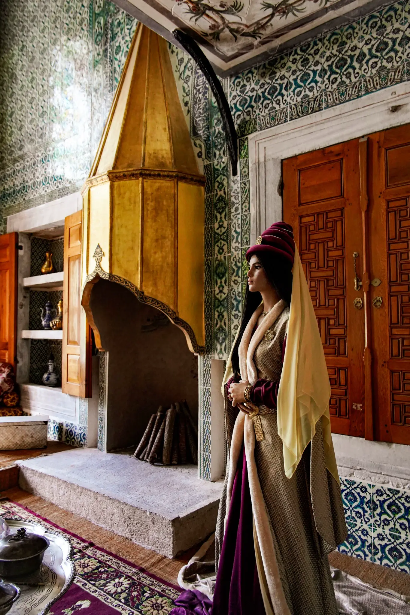 A costumed figure beside the conical hood of a Harem fireplace.