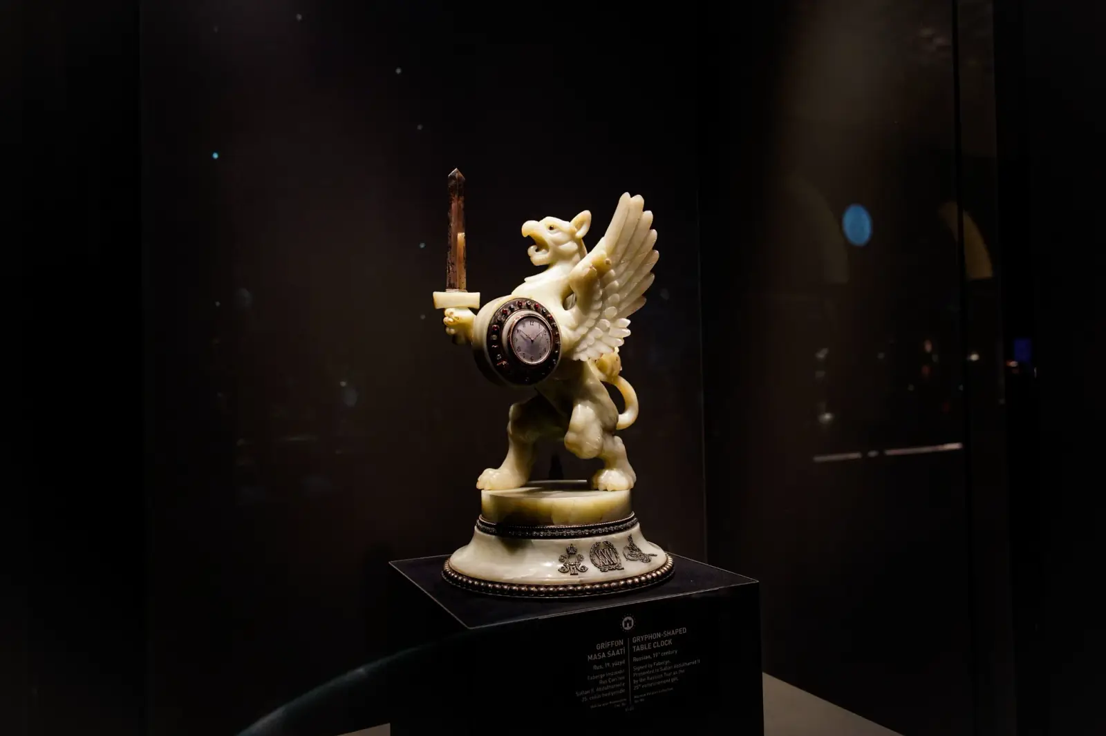 A carved automaton clock, a winged figure carrying the dial, in a darkened case.