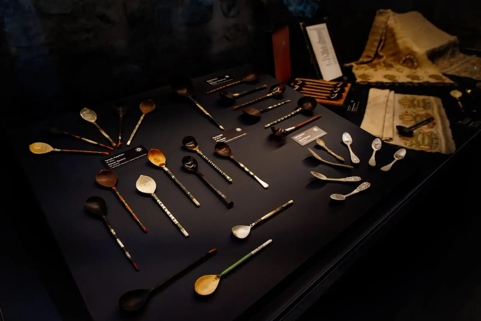 Spoons, forks and writing implements from the palace, laid out on a dark table.