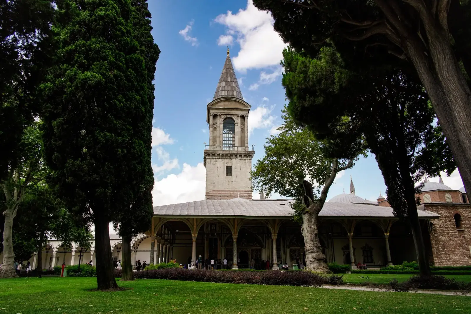 The Tower of Justice rising above the Second Courtyard, seen between cypresses and plane trees.
