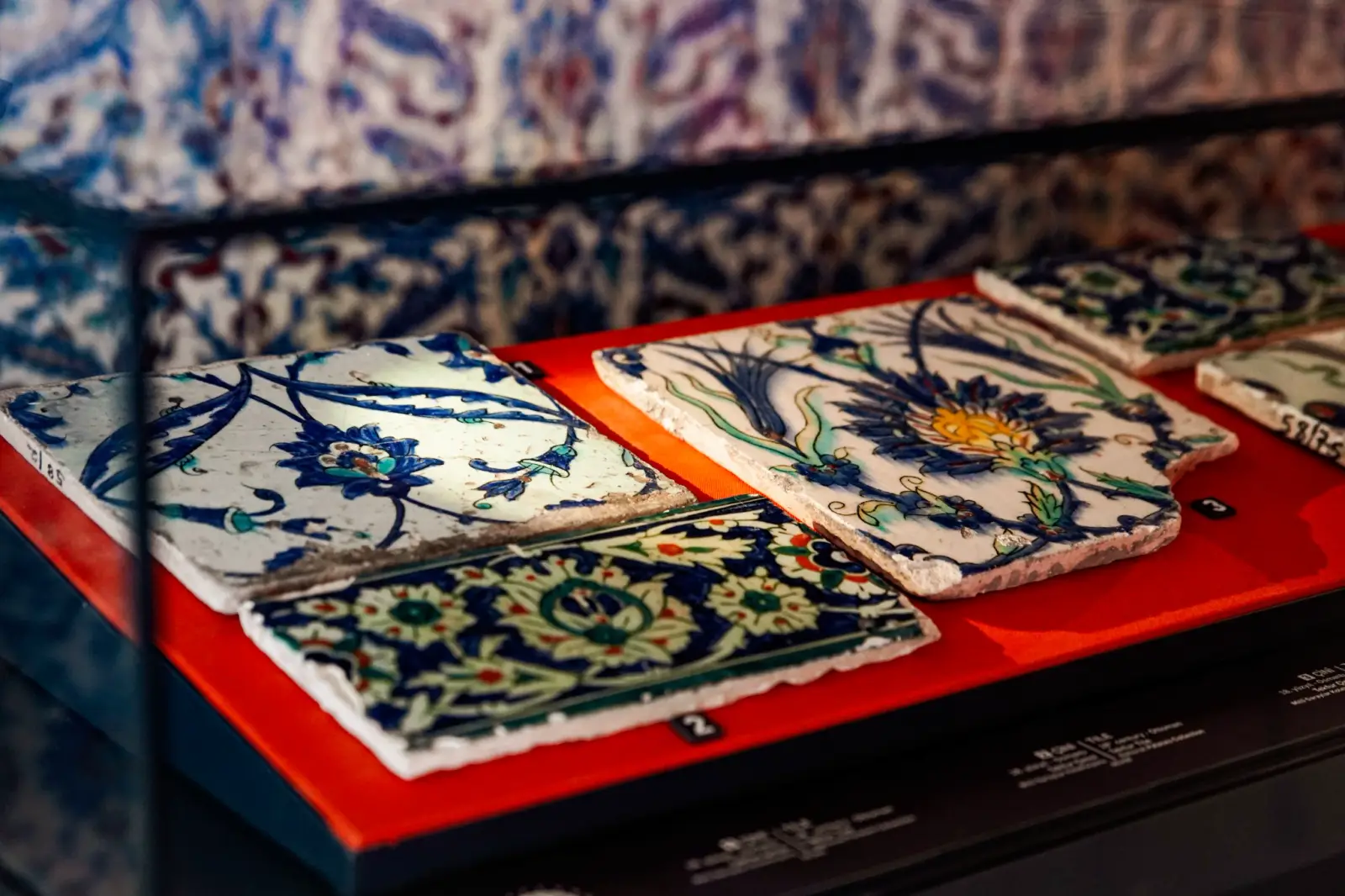 İznik tiles laid in a case, cobalt and turquoise floral designs on white.